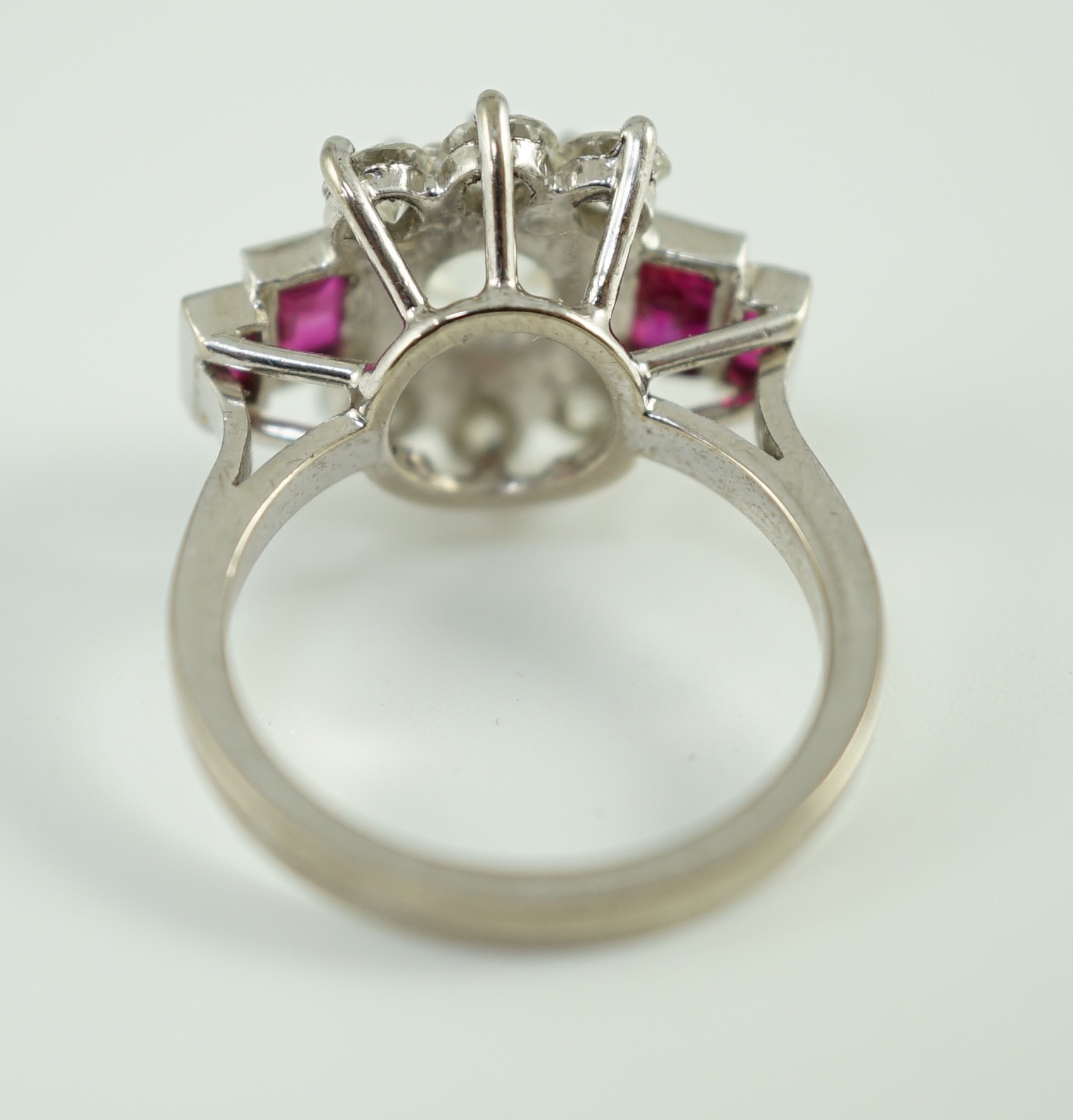 A platinum and single stone diamond dress ring, bordered by six round cut diamond and each shoulder set with two graduated rectangular rubies